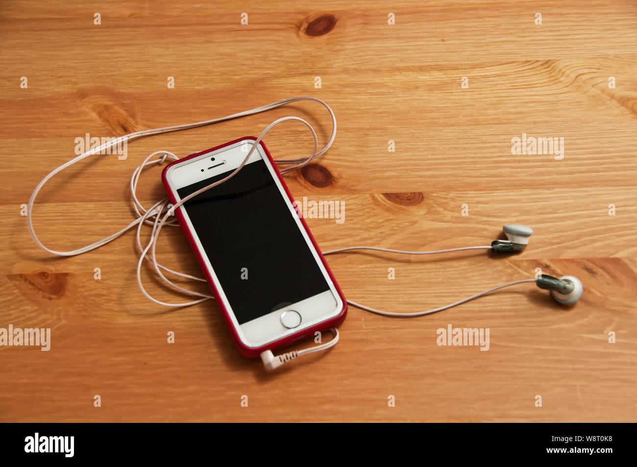 top down view of an iPhone and earpiece lying on a table Stock Photo
