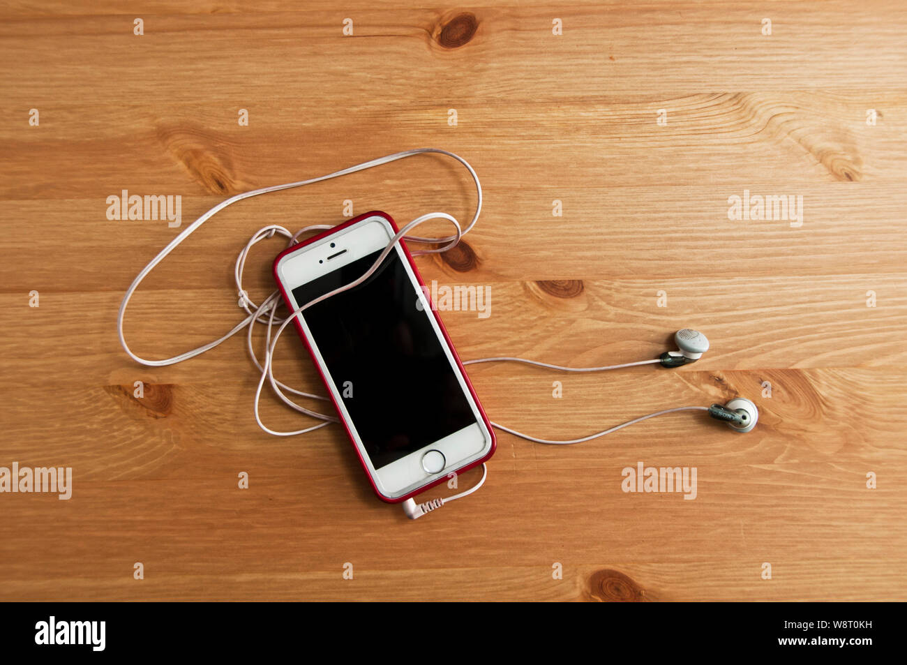 top down view of an iPhone and earpiece lying on a table Stock Photo
