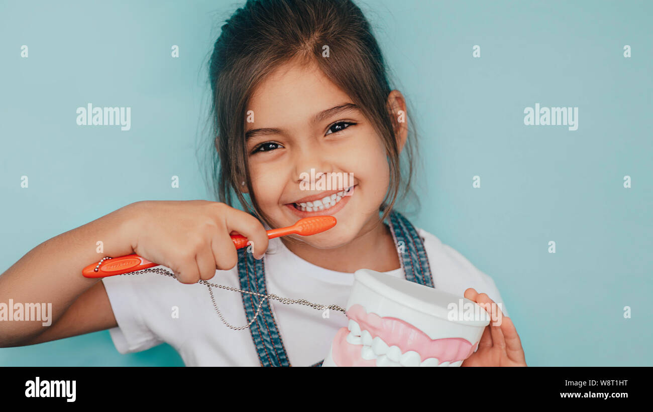 smiling mixed raced girl brushing teeth at blue background. Stock Photo