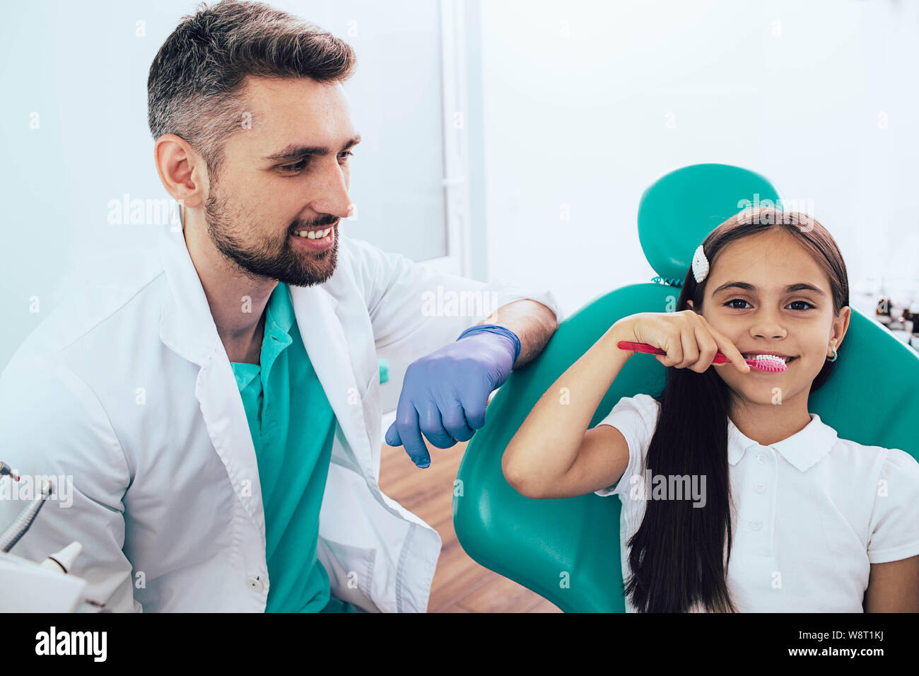 Dentist teaching little mixed race girl brushing teeth using human teeth model at dental clinic Stock Photo