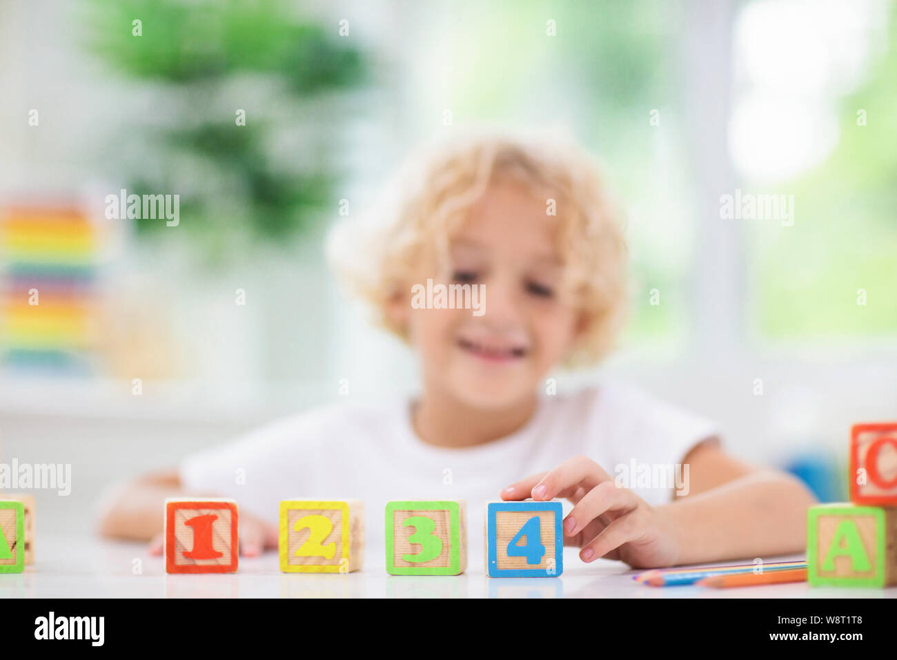 Child learning letters and numbers. Kid with colorful wooden abc blocks