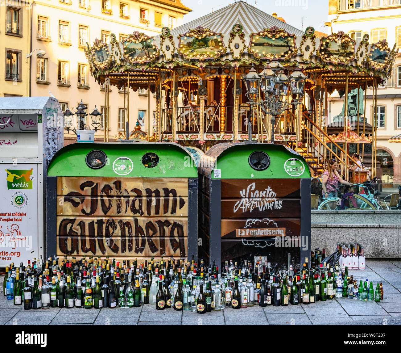 Empty glass bottles dumped in front of overflowing bottle banks, merry-go-round in background, Strasbourg, Alsace, France, Europe, Stock Photo