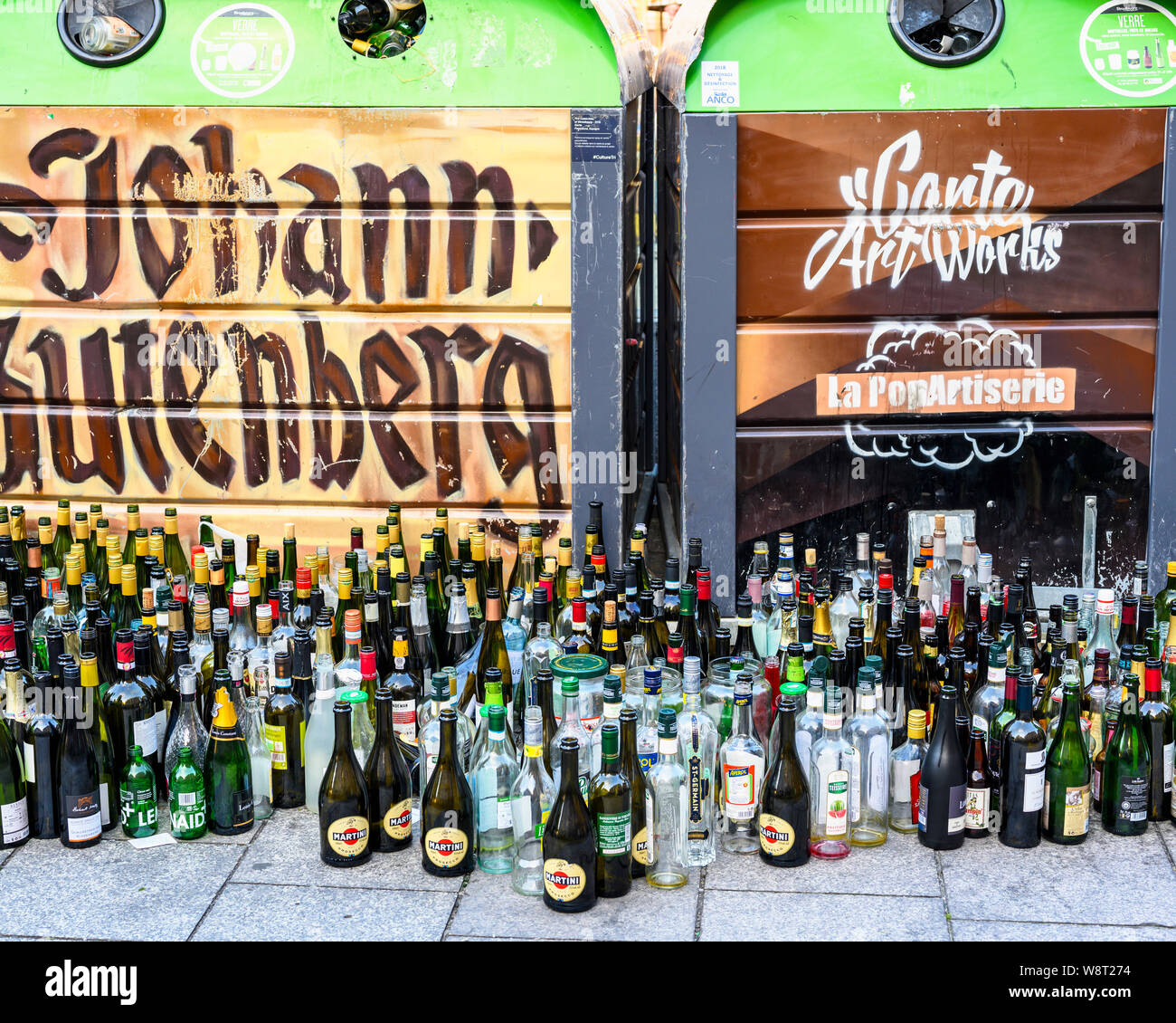 Empty glass bottles dumped in front of overflowing bottle banks