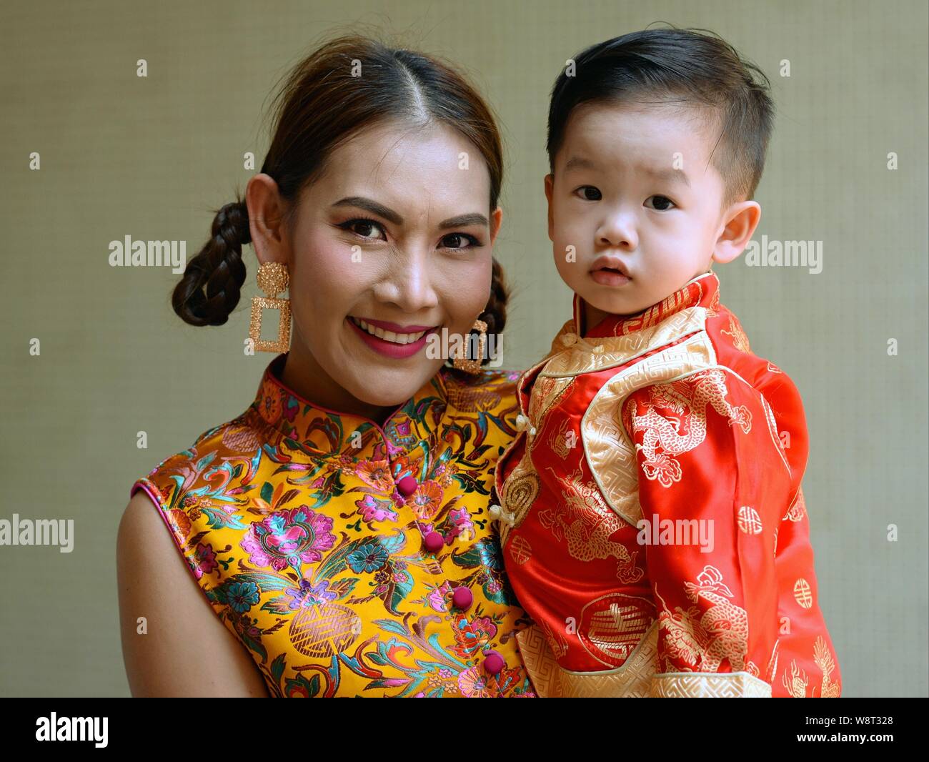 Dressed Up Thai Chinese Woman Holds Her Toddler Son In Her Arms
