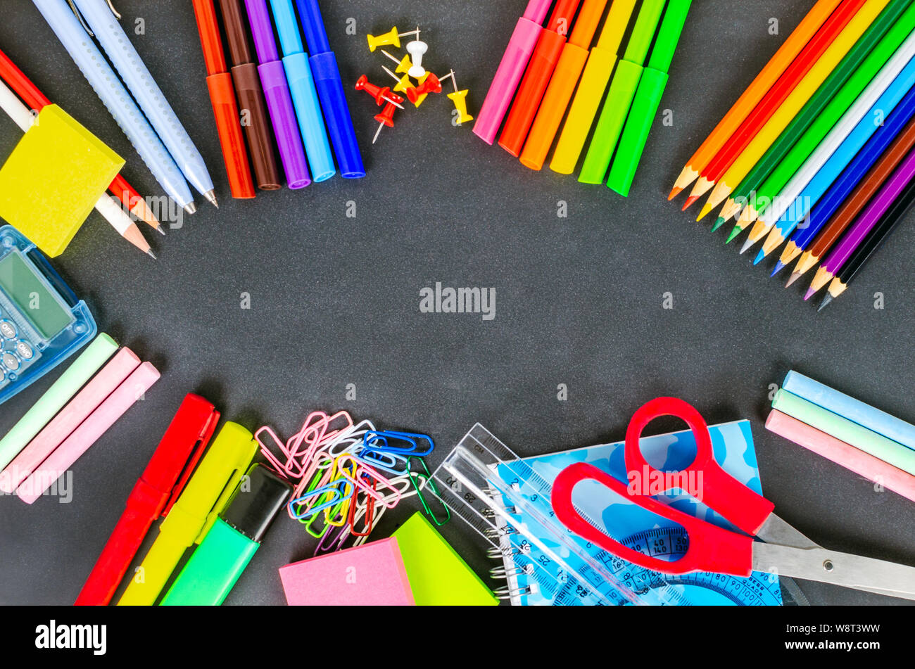 Colourful school supplies lying on a blackboard and copy space. Stock Photo
