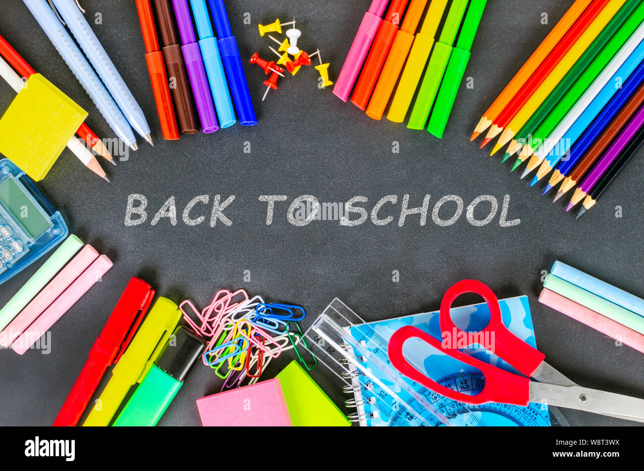Colorful school supplies on a blackboad with the text back to school. Concept of education. Stock Photo