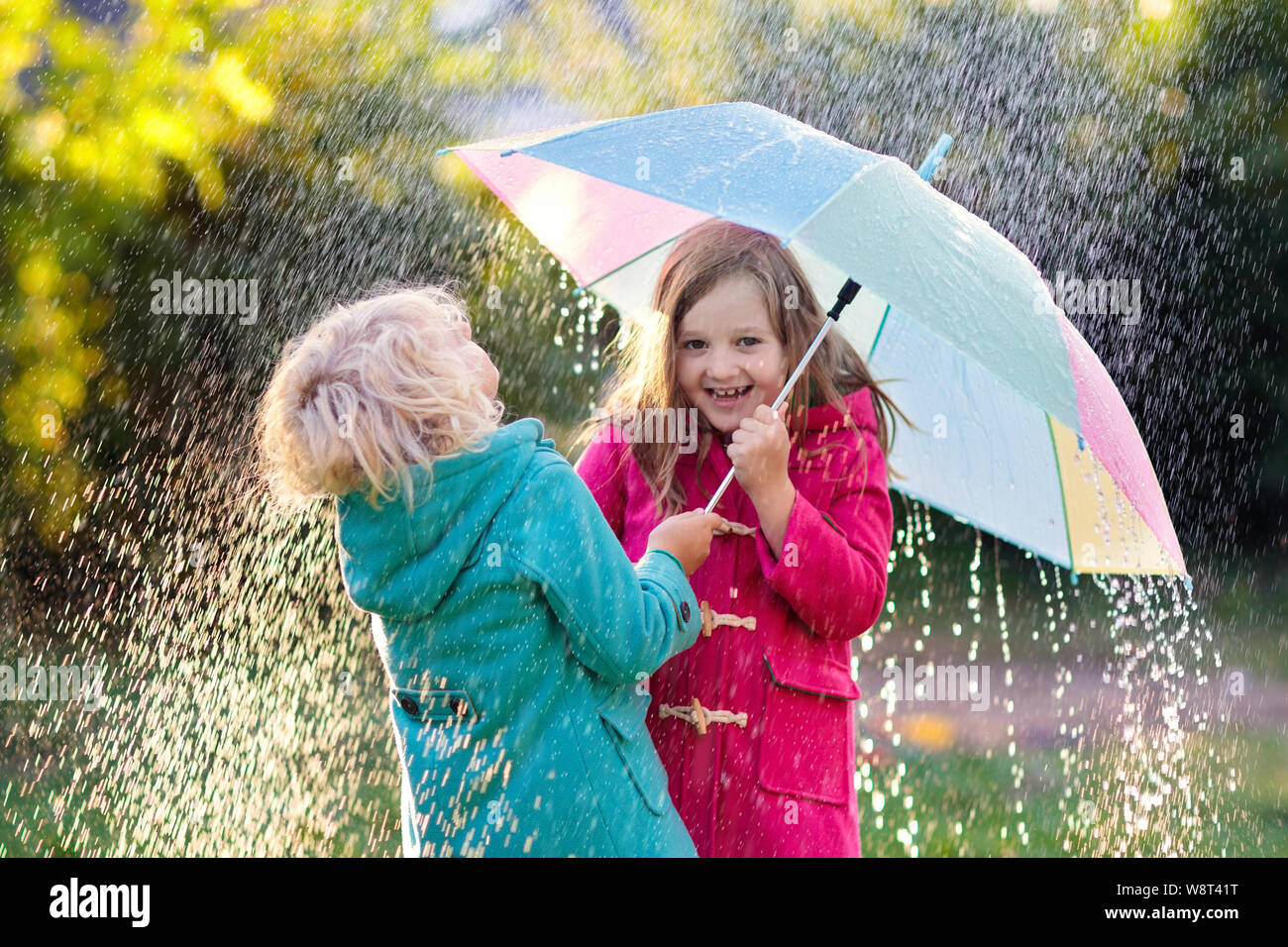 Kids with colorful umbrella playing in autumn shower rain. Little boy ...