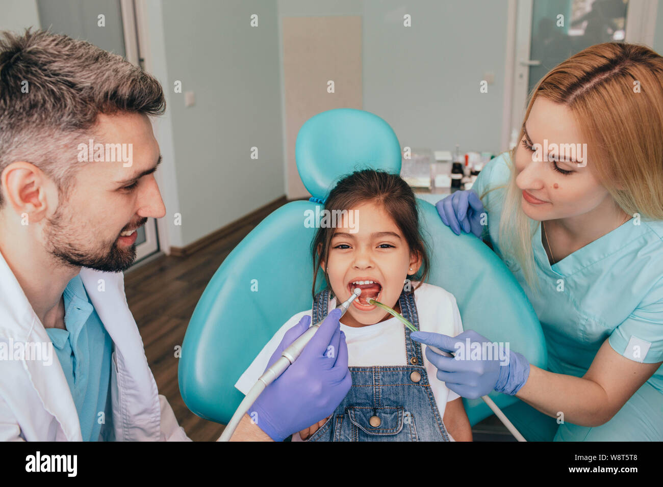 Assistants helping dentist in treatment patient's teeth in medical clinic Stock Photo