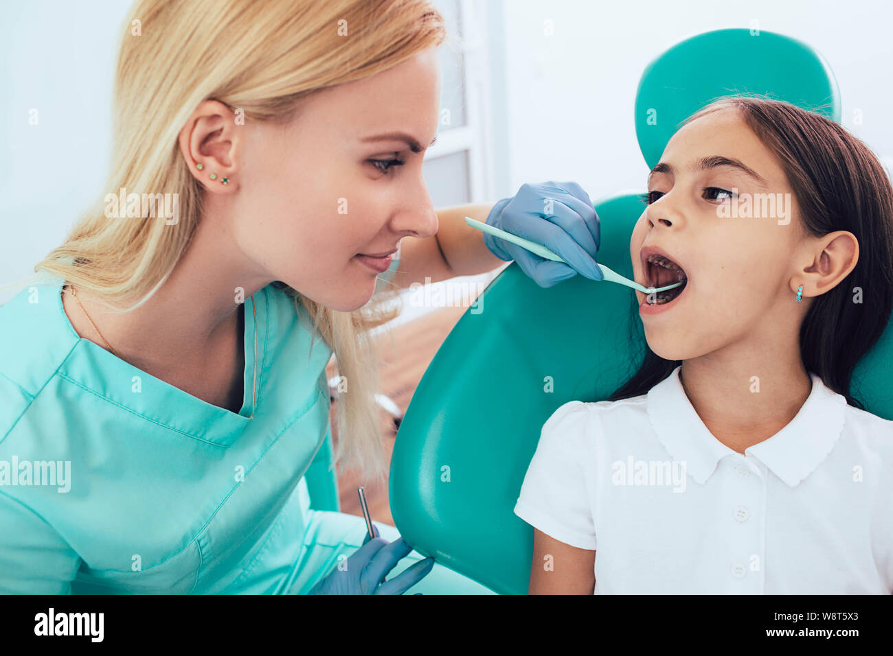 Little girl getting teeth exam by pediatric dentist at clinic Stock Photo