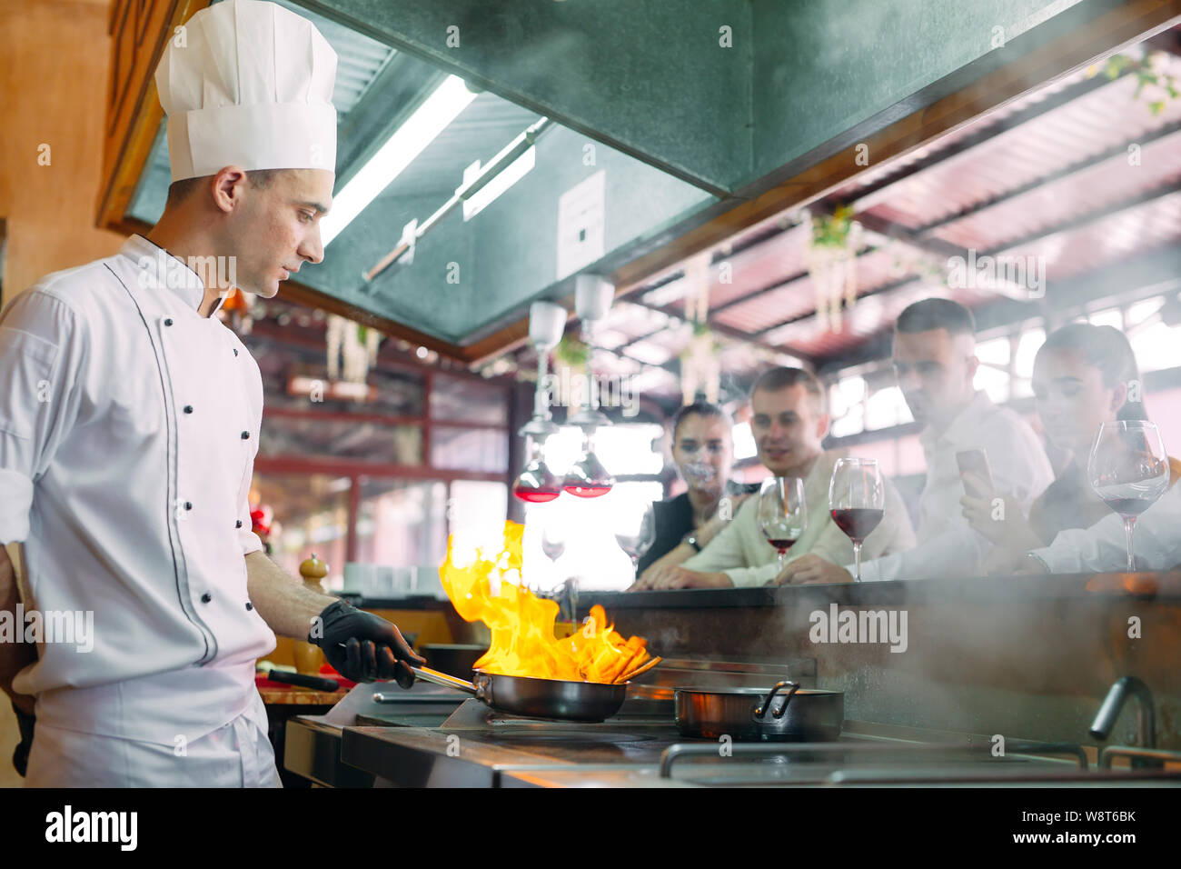 The chef prepares food in front of the visitors in the restaurant Stock Photo