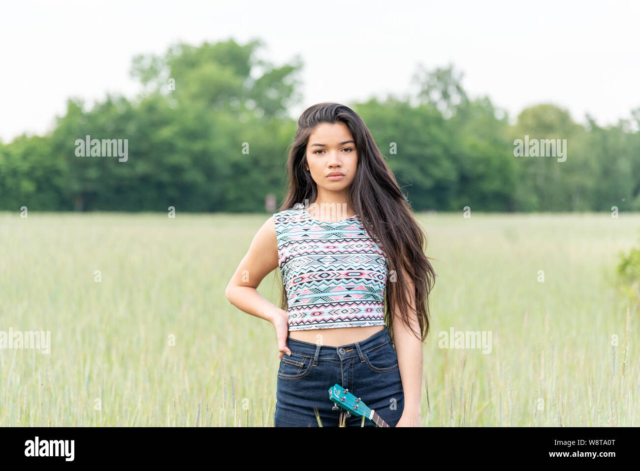 young beautiful asian woman with very long hair and a ukulele outdoors Stock Photo