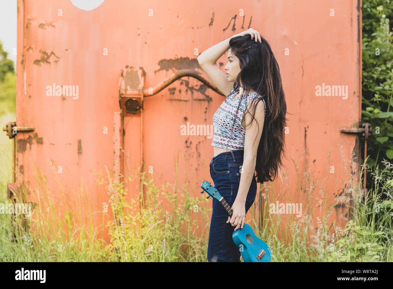 young beautiful asian woman with very long hair and a ukulele outdoors Stock Photo