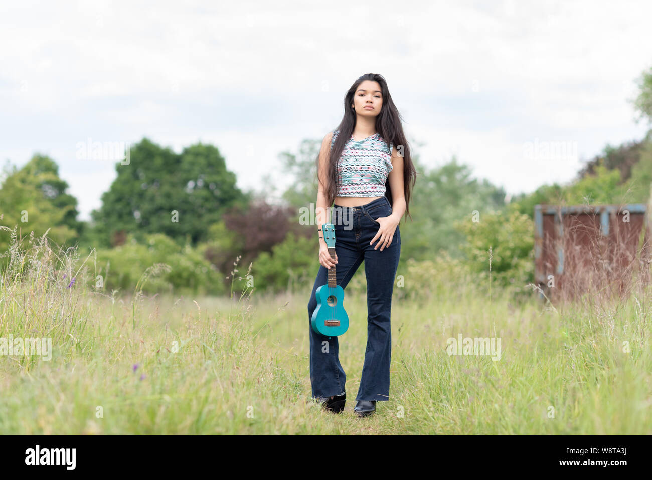 young beautiful asian woman with very long hair and a ukulele outdoors Stock Photo