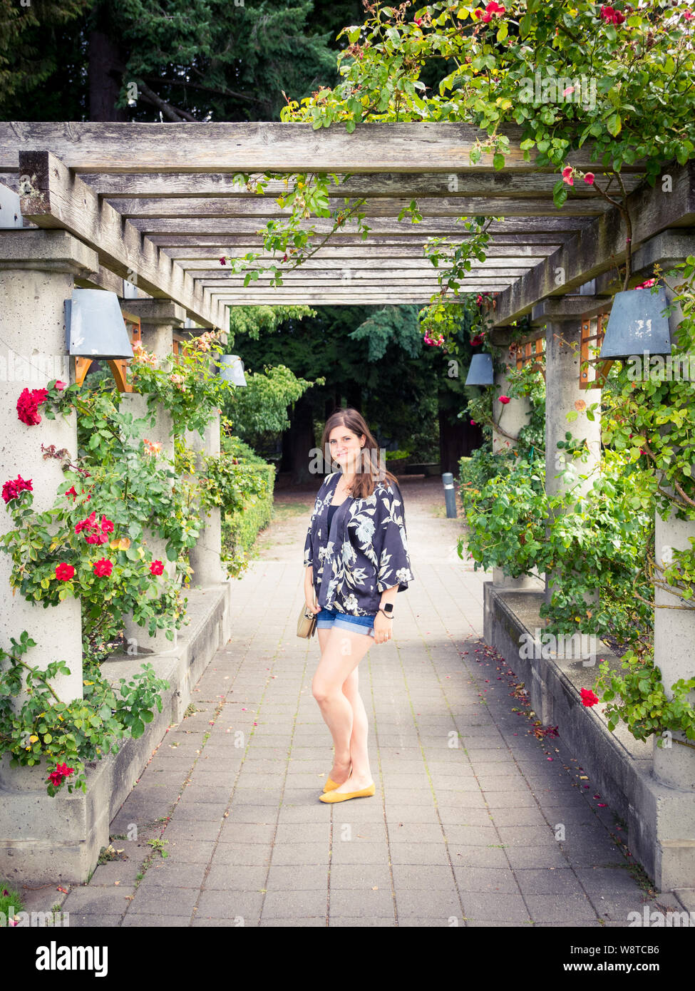 A pretty girl under an arbour of roses in the UBC Rose Garden
