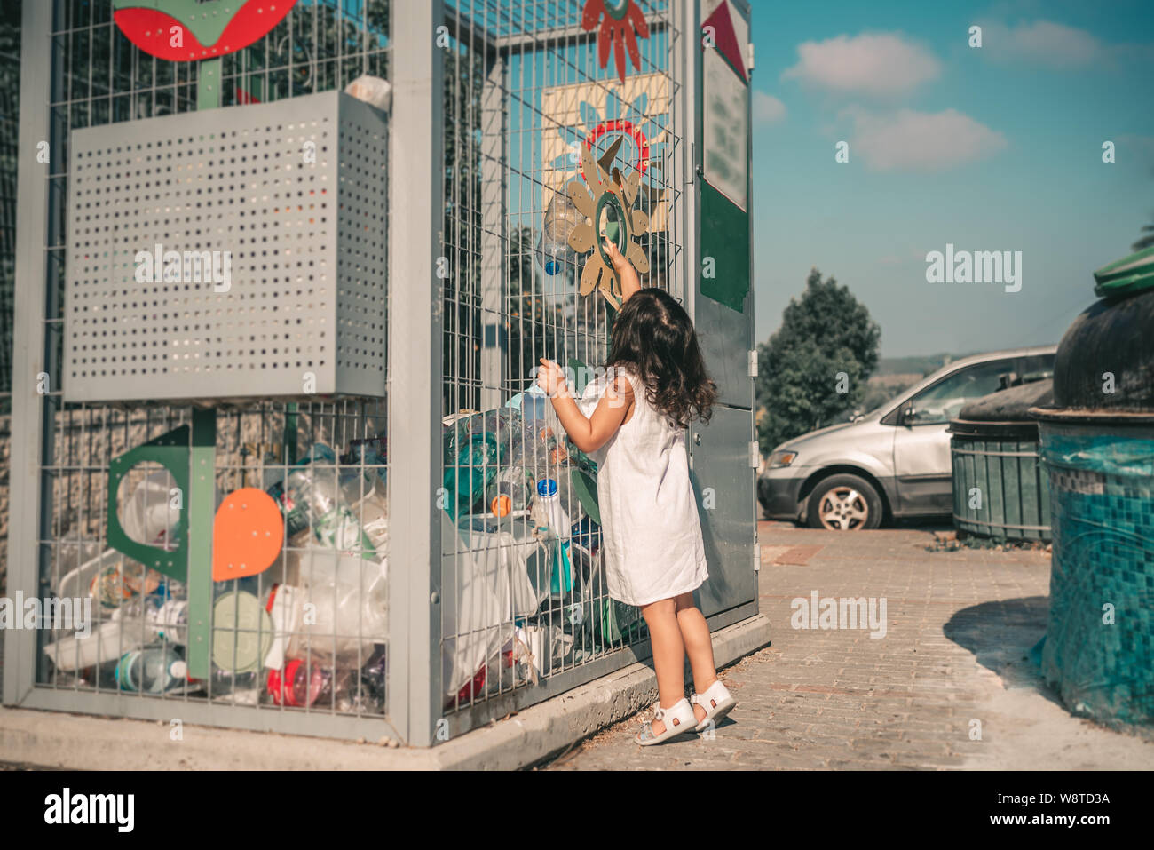 Little Girl Recycling Empty Plastic Water Bottles in Metal Recycling