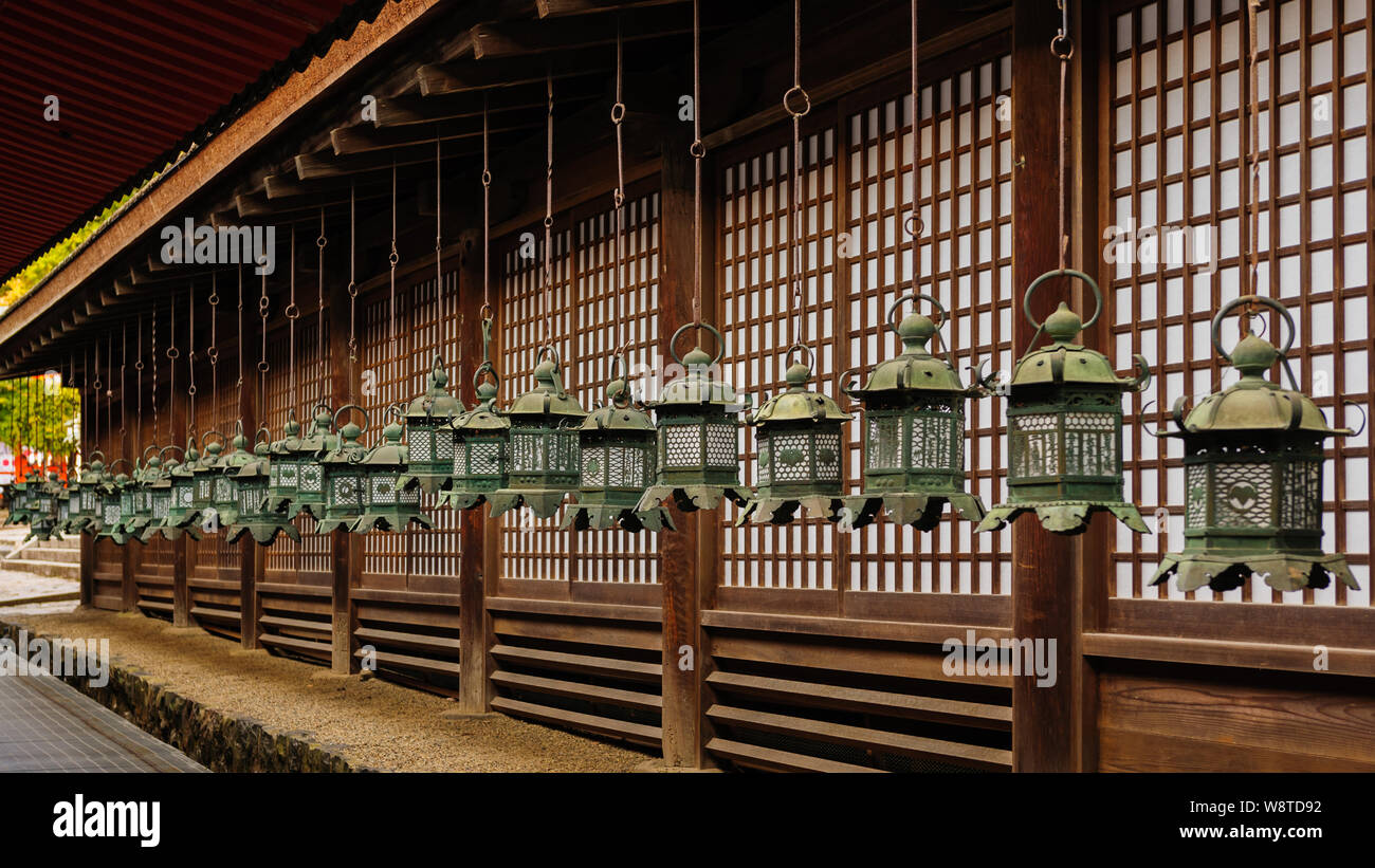 Group of traditional bronze lanterns hanging from the roof of shrine main building in Naras Kasuga Taisha delivering a pattern, Japan November 2018 Stock Photo