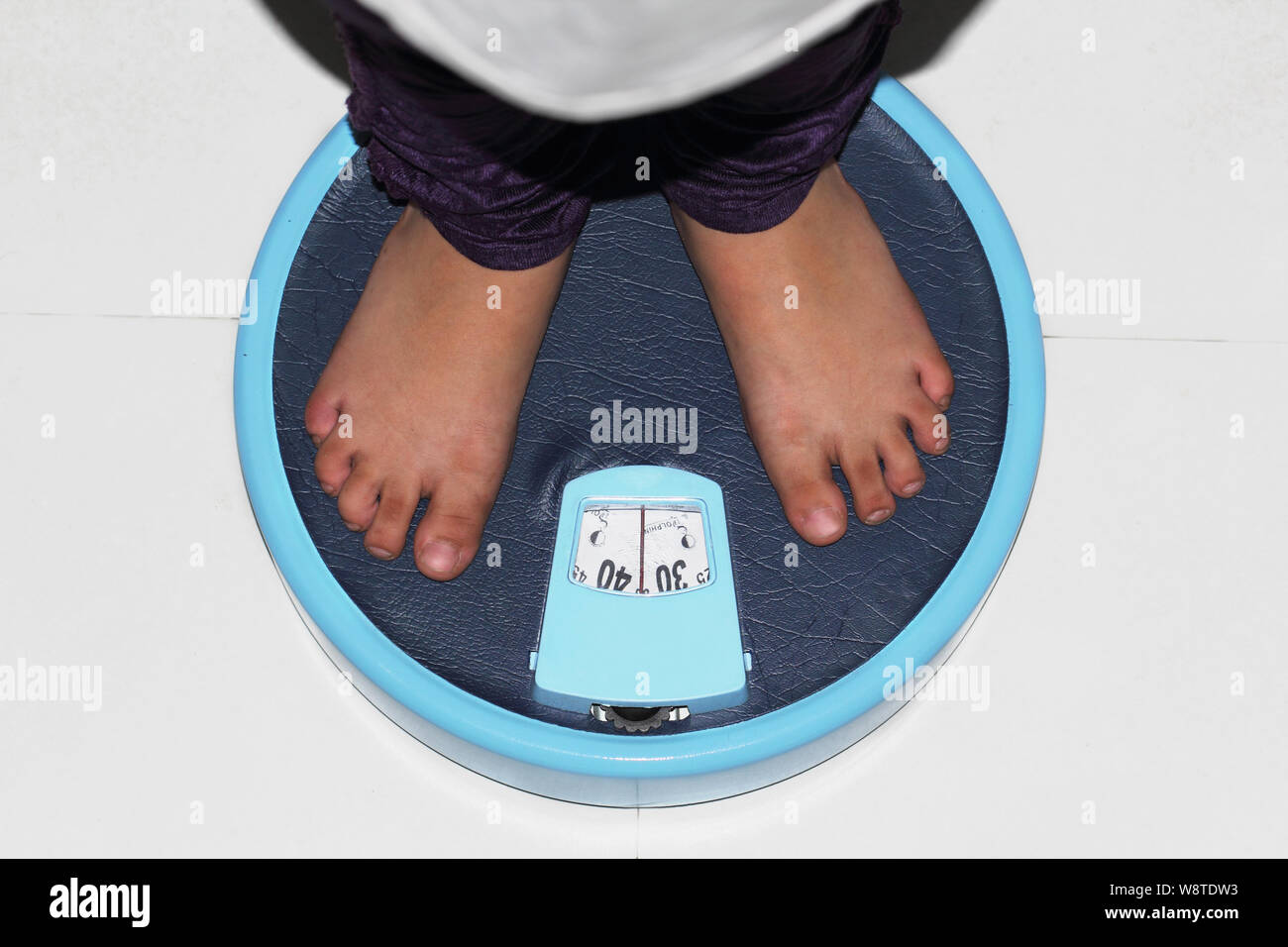 Child weighing itself on a bathroom scale Stock Photo