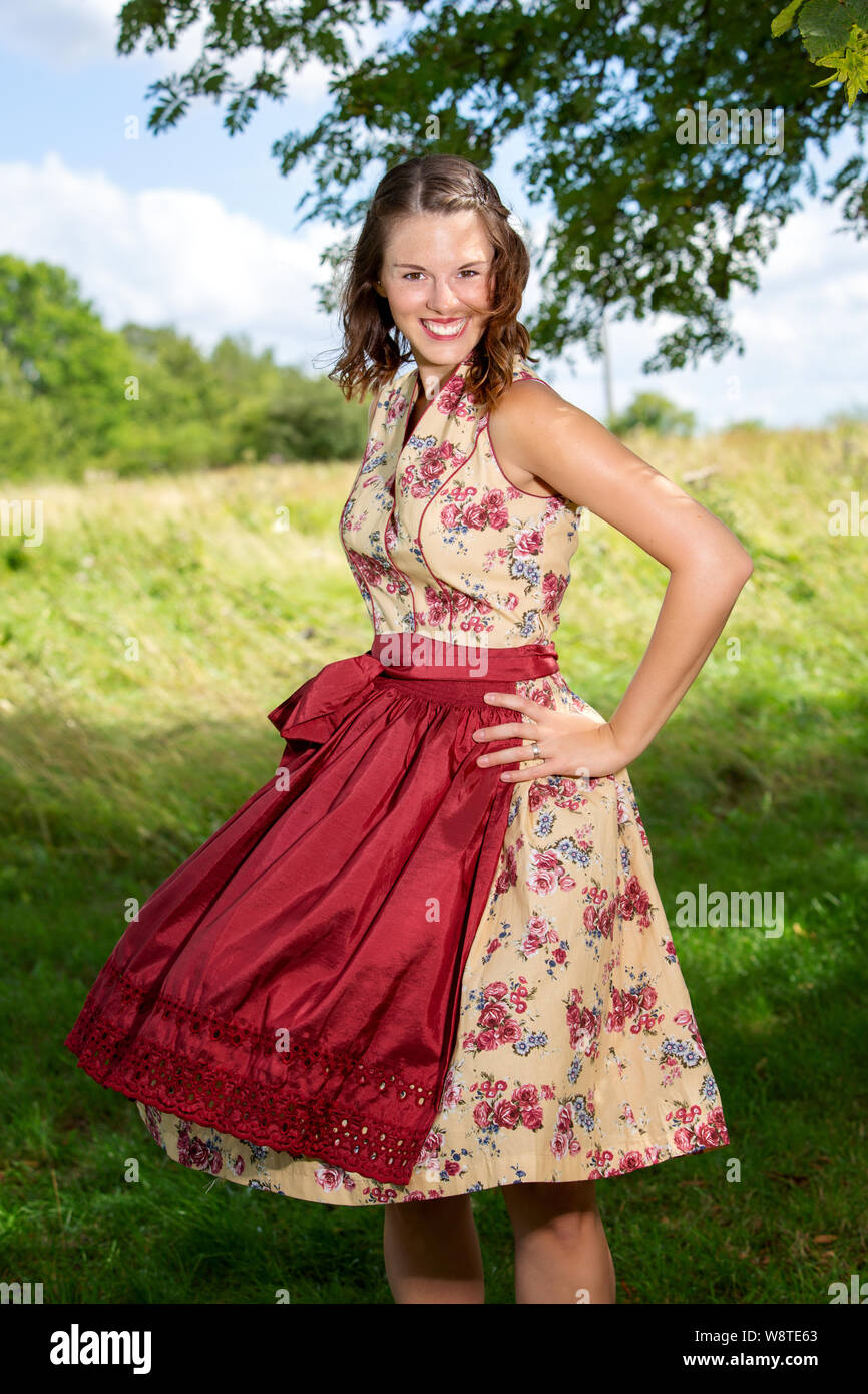 portrait of young woman in dirndl standing outdoors by a tree Stock Photo