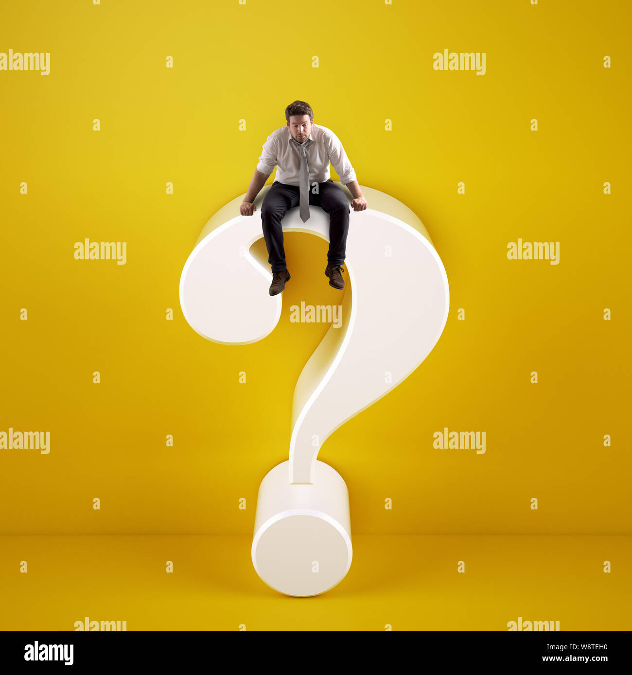 Man sitting on top of a big white question mark on a yellow background Stock Photo