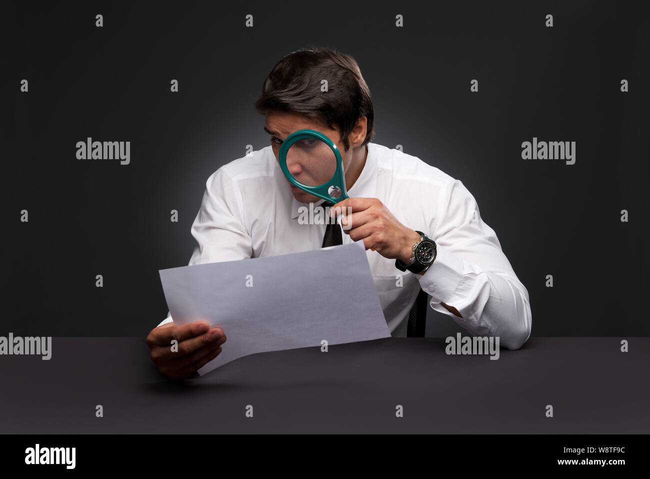 Businessman looking a document through magnifying glass Stock Photo