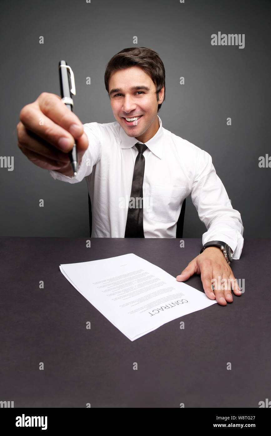 Businessman showing a pen while signing a document in office Stock Photo