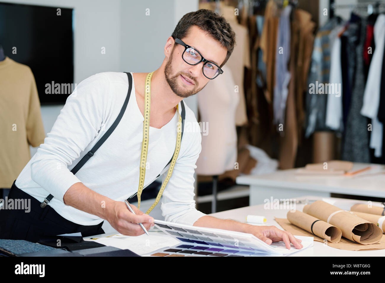Young professional fashion designer with measuring tape looking at you Stock Photo