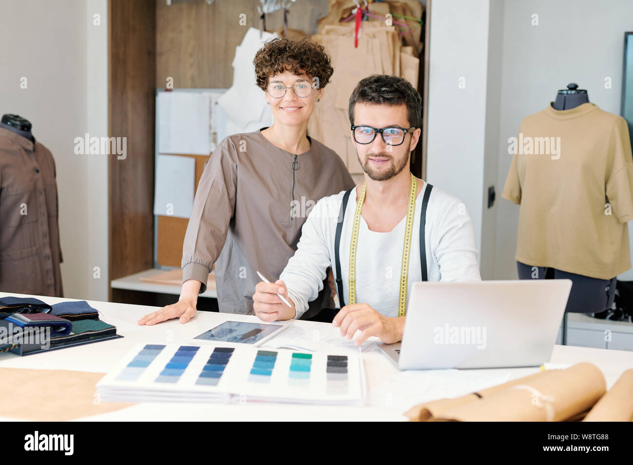 Young successful fashion designers using mobile gadgets while working in studio Stock Photo