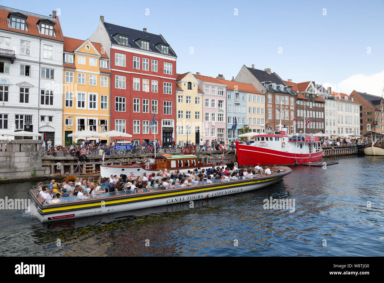 Denmark tourism - Copenhagen canal tour; Tourists in a tourist boat in colourful Nyhavn harbour, Copenhagen Denmark Europe Stock Photo