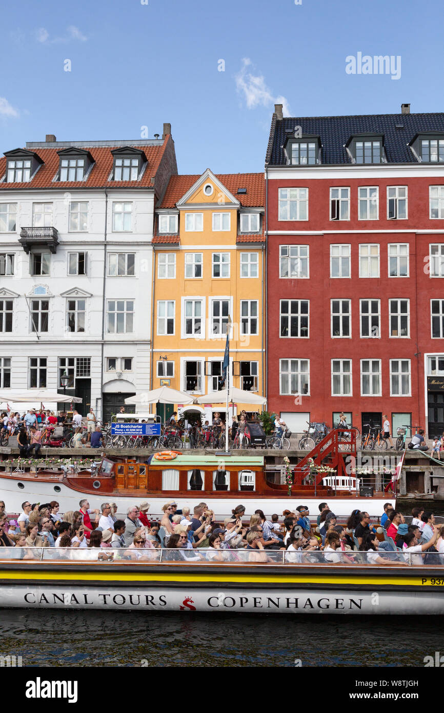 Denmark tourism - Copenhagen canal tour; Tourists in a tourist boat in colourful Nyhavn harbour, Copenhagen Denmark Europe Stock Photo