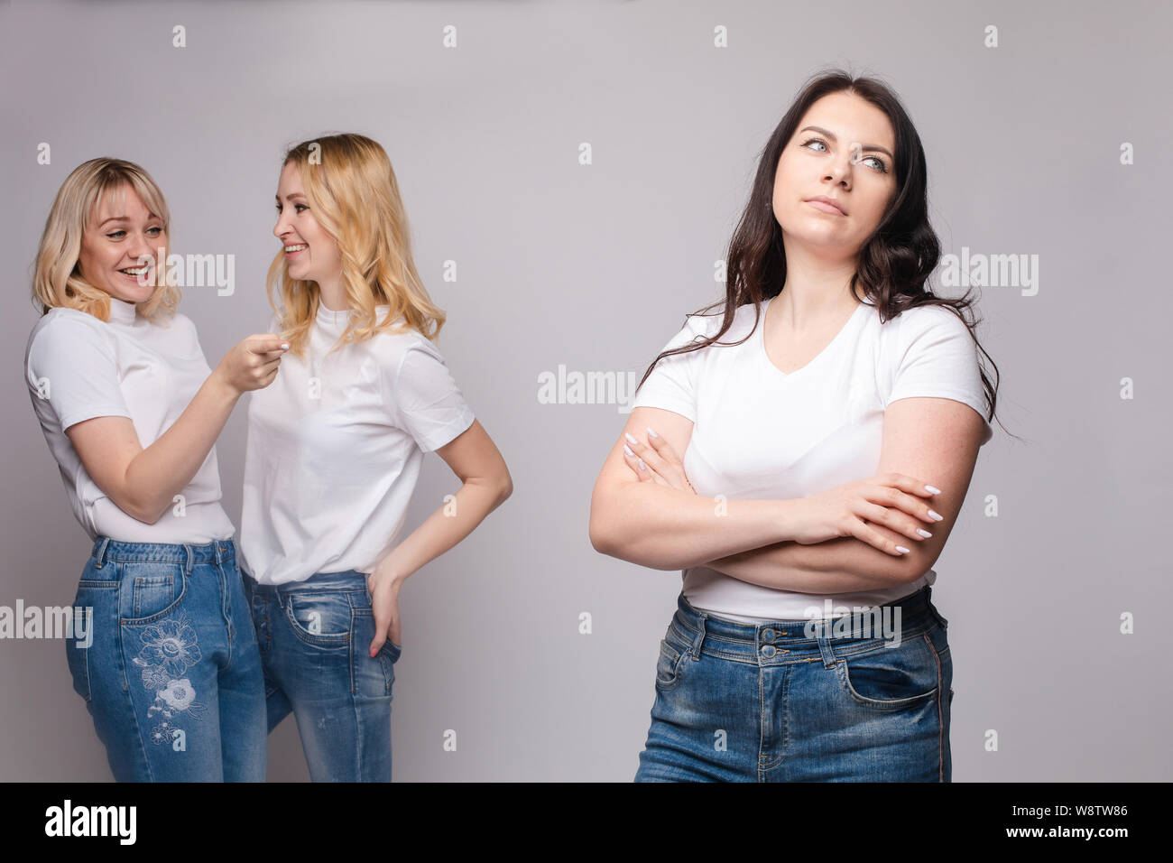 Offended brunette and two blondes gossiping behind Stock Photo