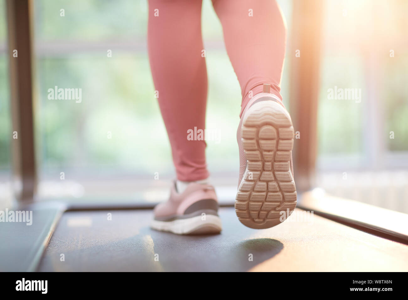 Back view of female feet running on treadmill during cardio workout in