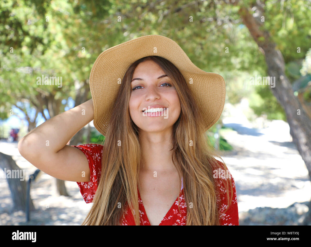 Portrait of a beautiful smiling girl wearing hat and red dress looking ...