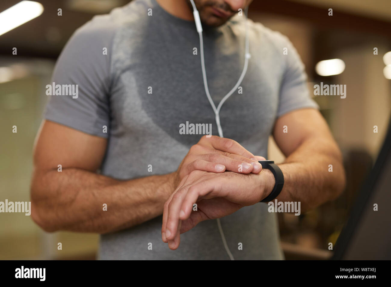 Mid section portrait of unrecognizable man checking smartwatch while working out in gym, copy space Stock Photo