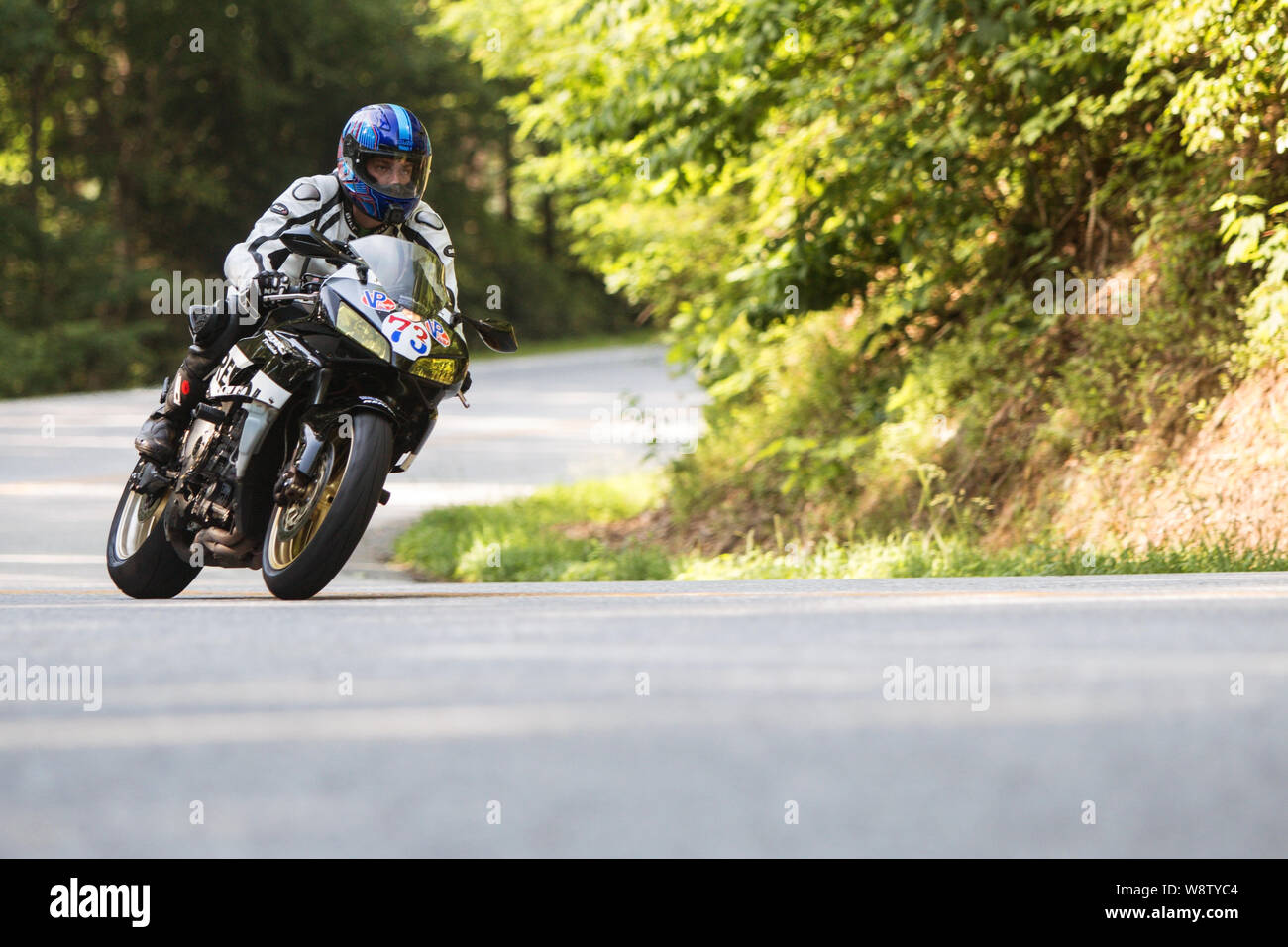 A man riding a motorcycle leans into a turn at a high rate of speed, as he traverses windy roads on a weekend ride on June 9, 2018 in Blairsville, GA. Stock Photo