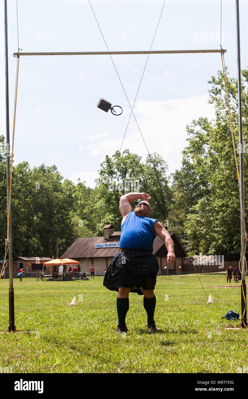 A man slings a 42 pound weight backwards, high over a bar in the weight over bar event, at the Blairsville Scottish Highland Games in Blairsville, GA. Stock Photo