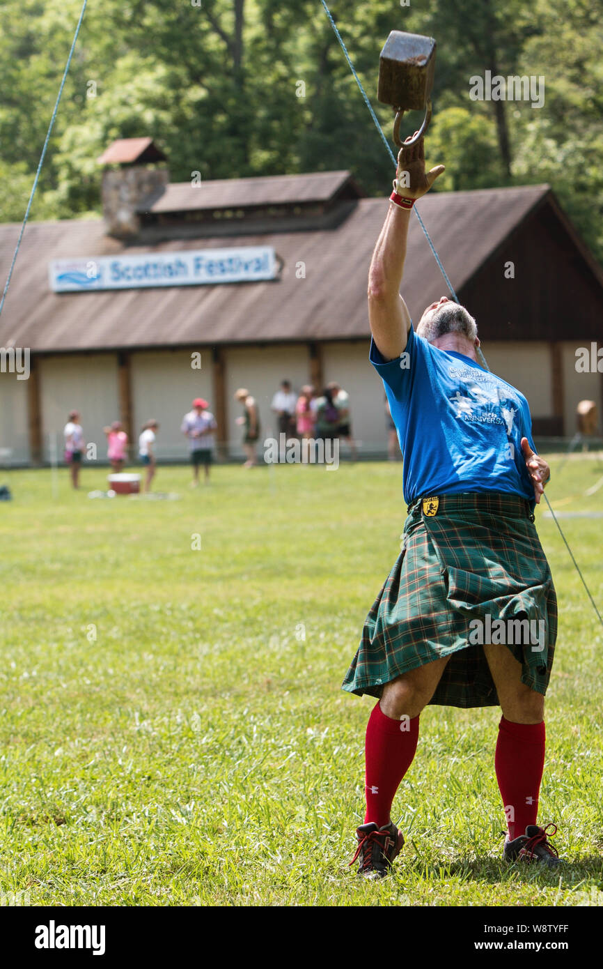 A man competes in the weight over bar event, tossing a 42 pound weight over a bar, at the Blairsville Scottish Highland Games in Blairsville, GA. Stock Photo