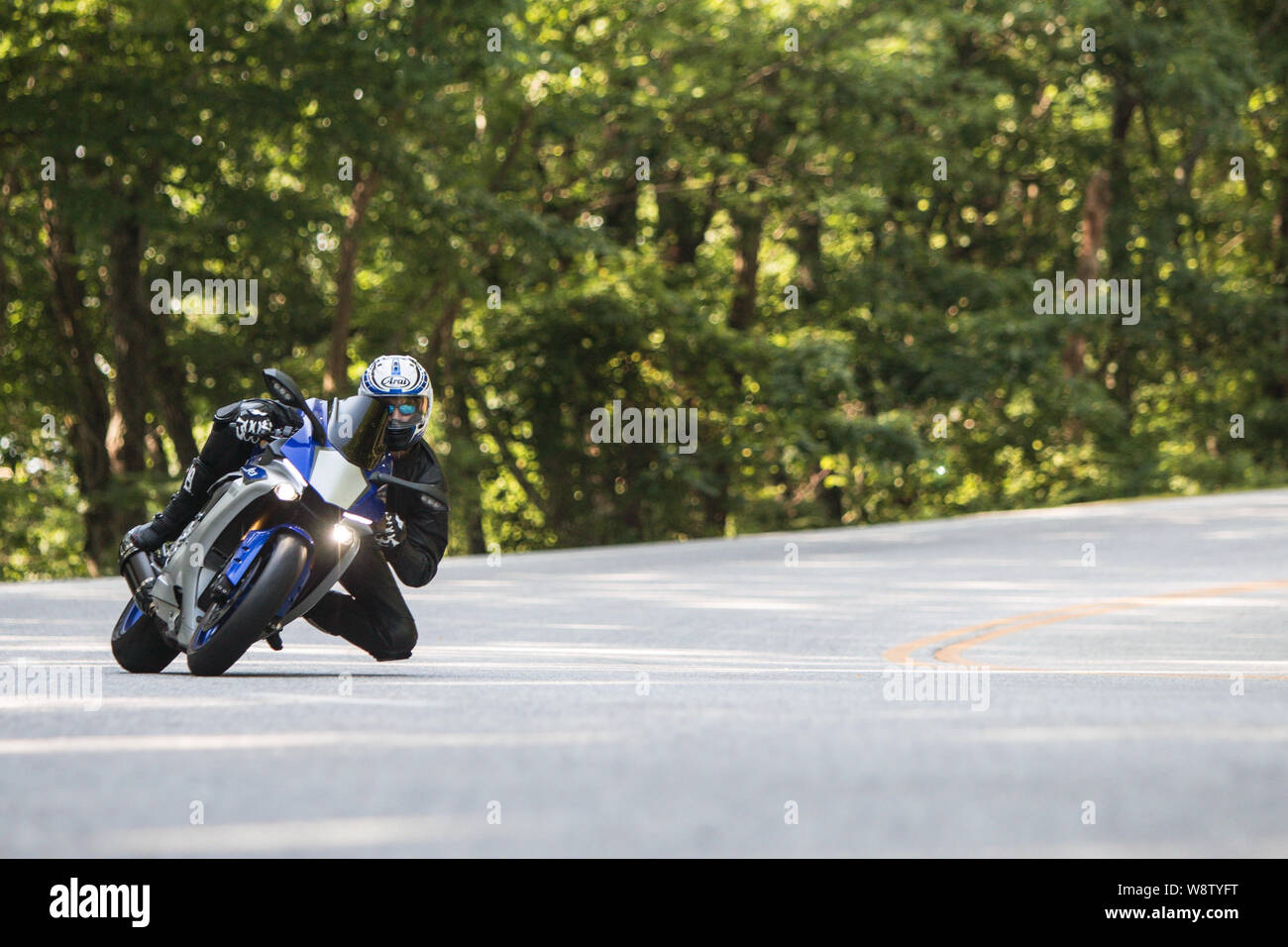 A man riding a road racing motorcycle leans into a turn at a high rate of speed, as he traverses windy roads on June 9, 2018 in Blairsville, GA. Stock Photo