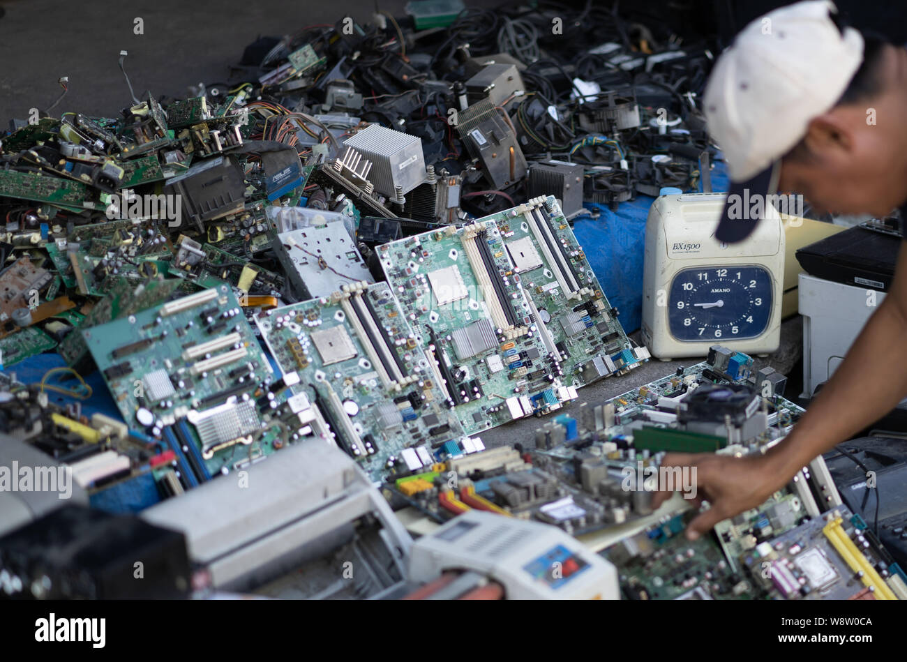 A man looks through old circuit boards for sale on a sidewalk,Cebu City,Philippines Stock Photo