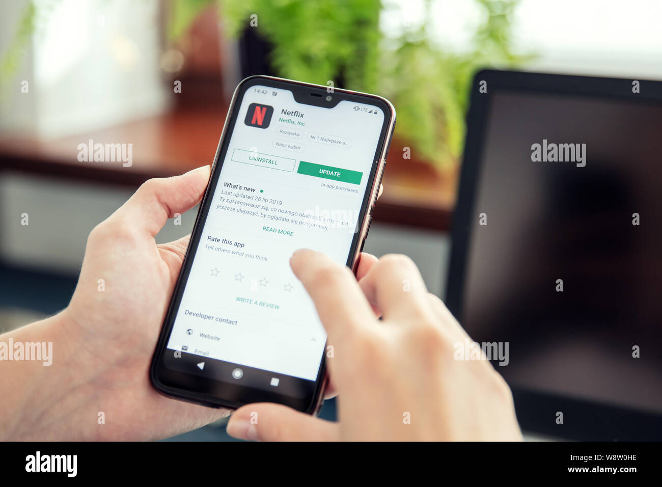 WROCLAW, POLAND - JULY 31th, 2019: Woman installs Netflix application on the Xiaomi A2 smartphone. Netflix is an American media-services provider whic Stock Photo