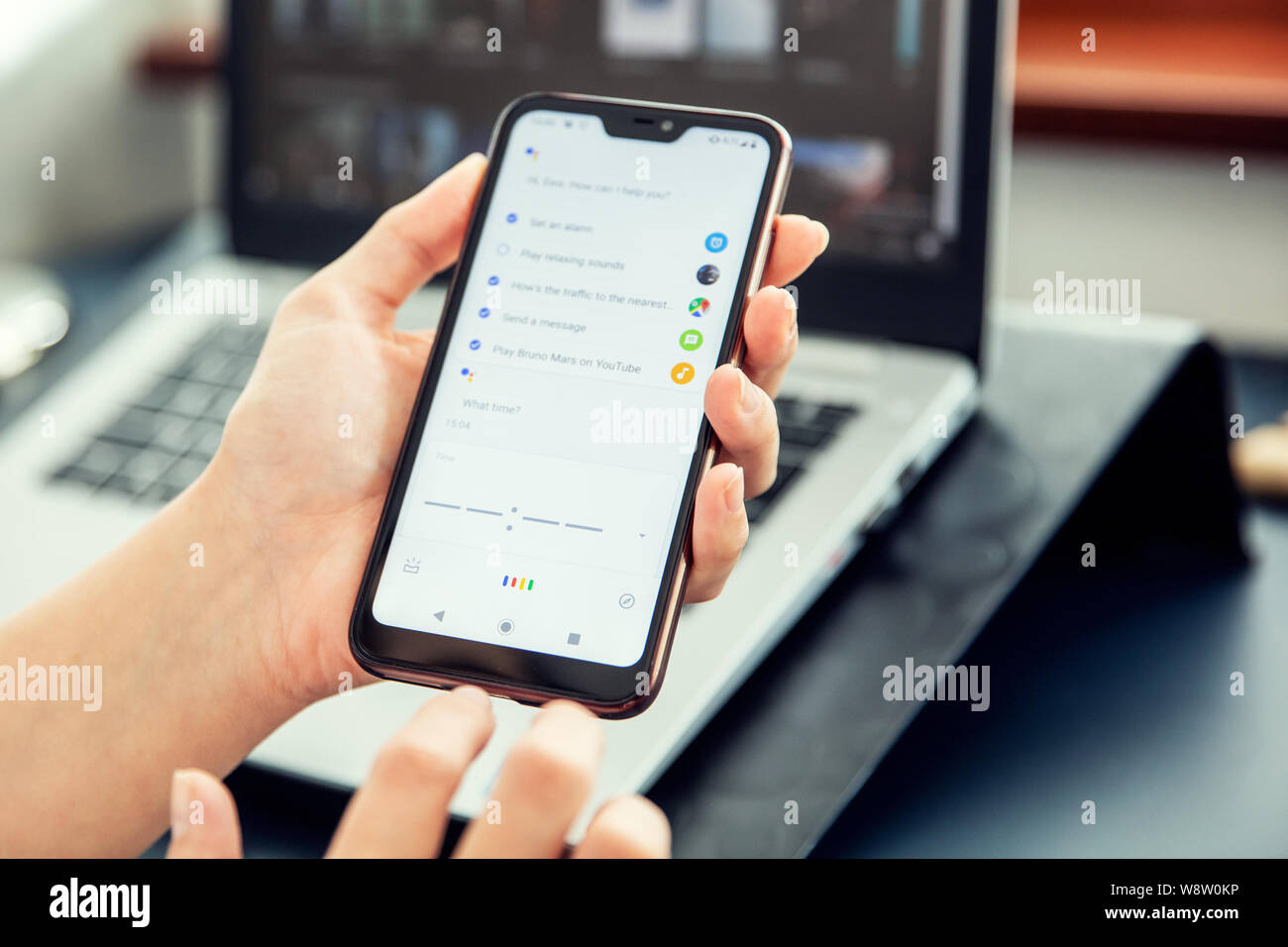 WROCLAW, POLAND - JULY 31th, 2019: Woman uses google assistant on xiaomi a2 smartphone. Google Assistant is an artificial intelligence-powered virtual Stock Photo