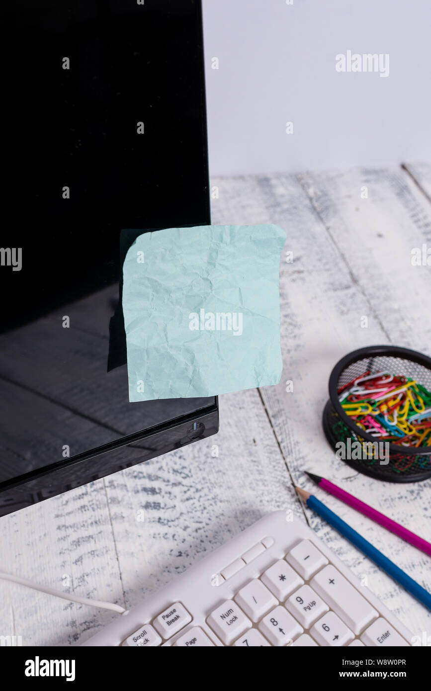 Note paper taped to black computer screen near keyboard and stationary