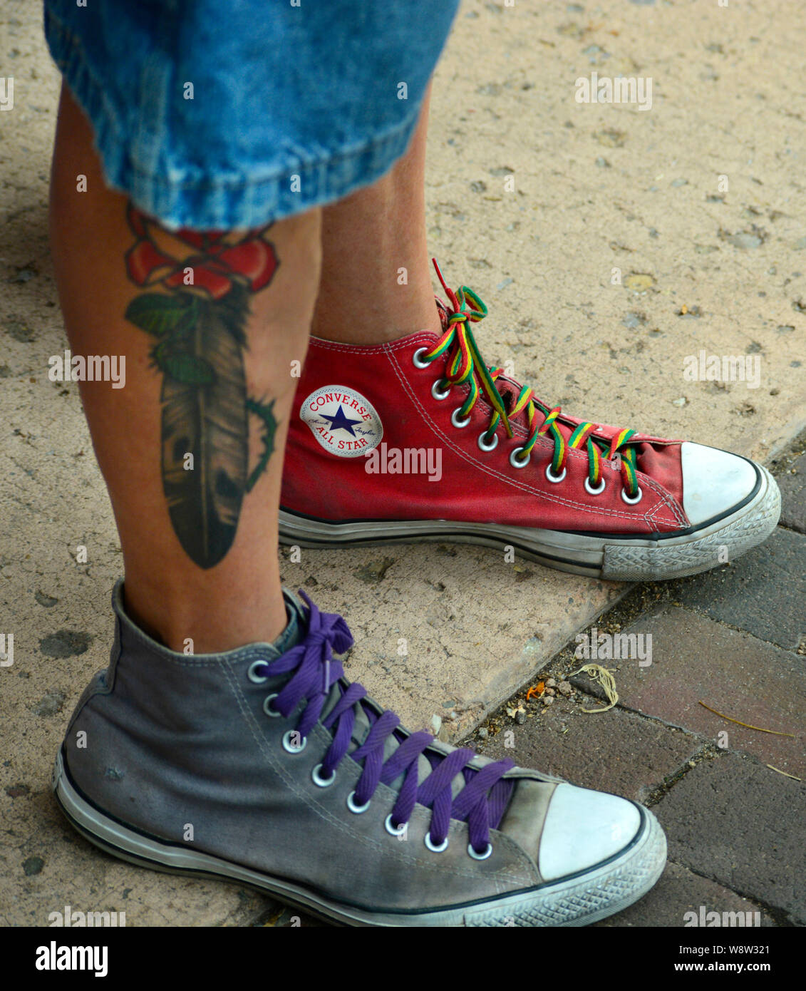 Young man wears mismatched Converse brand tennis shoes Stock Photo