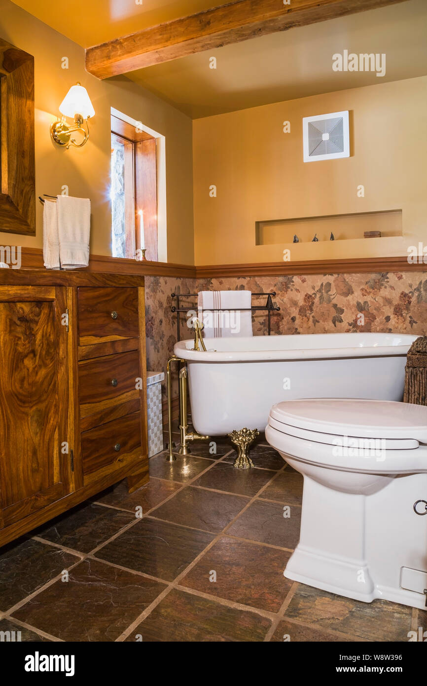 White antique rolltop bathtub with clawfoot legs, toilet, teak wood