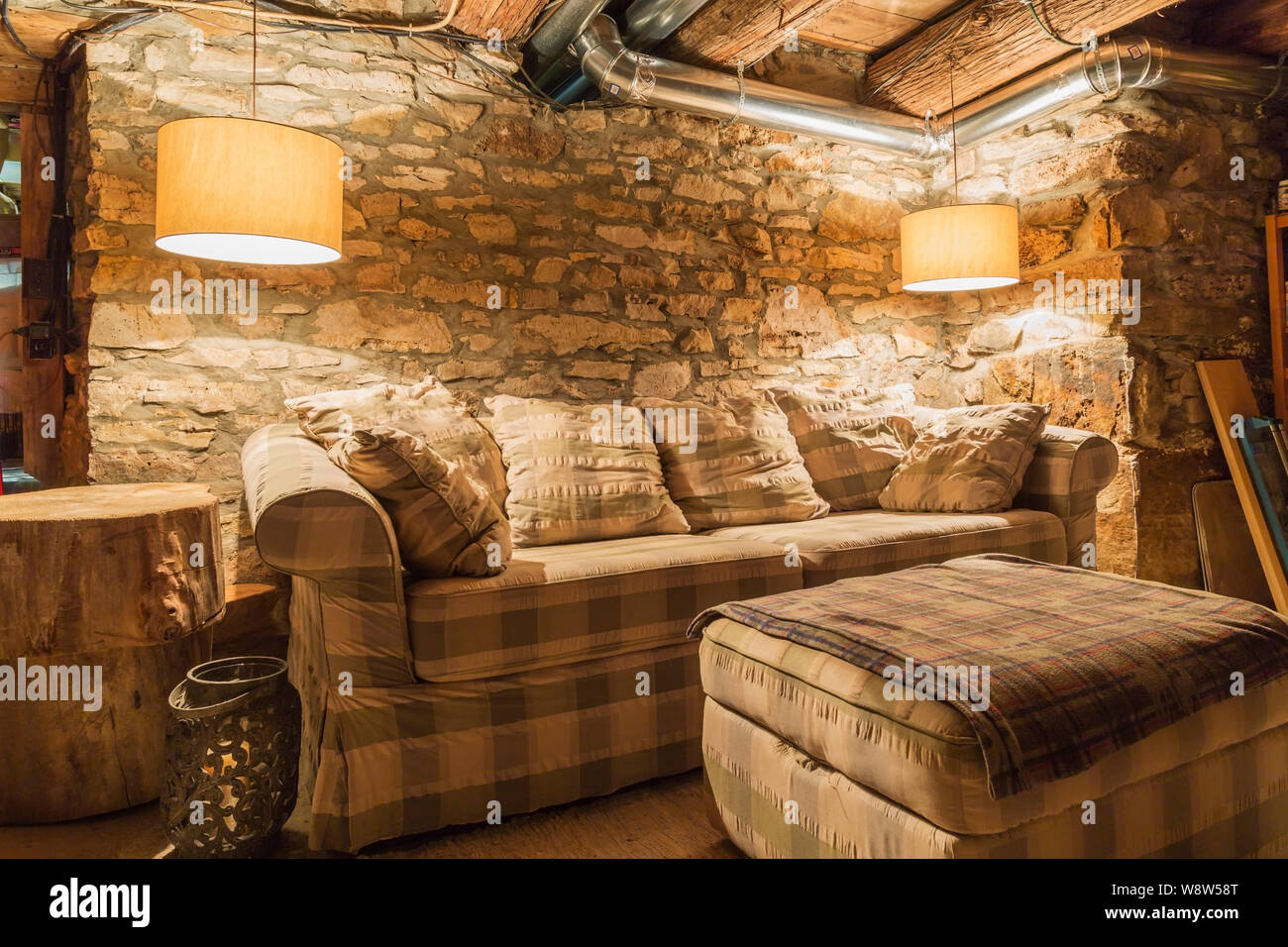 Tartan sofa-bed against original foundation fieldstone wall in basement room inside an old 1820 cottage style cut stone and fieldstone house Stock Photo
