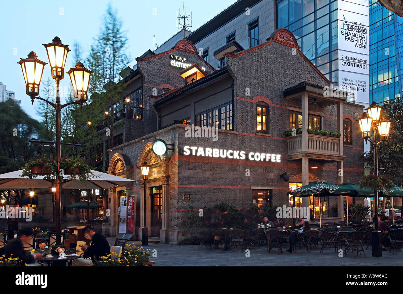 Customers drink coffee at the Starbucks Coffee cafe at Xintiandi, a tourist attraction complex