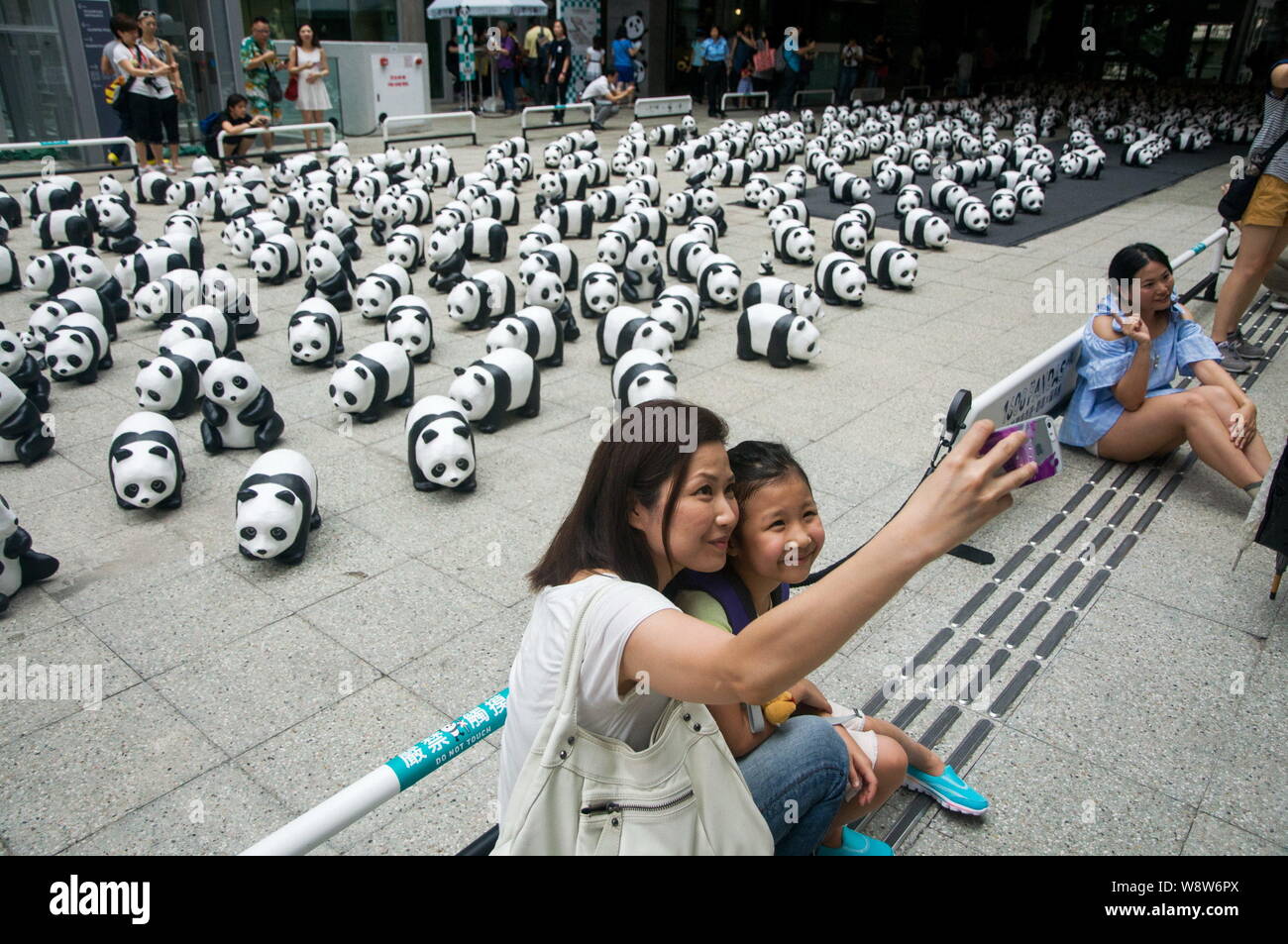 Visitors take selfies in front of the paper pandas created by French artist Paulo Grangeon at PMQ, a comprehensive design and exhibition complex renov Stock Photo