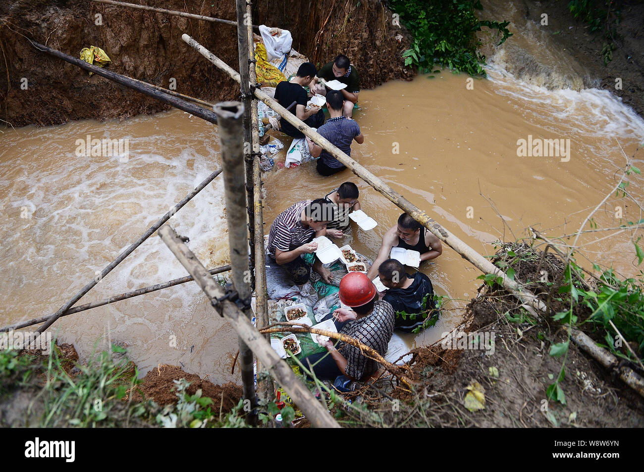 Rescue workers use their bodies to block the breach as they eat their lunches in the muddy water in Chengdu city, southwest Chinas Sichuan province, 9 Stock Photo