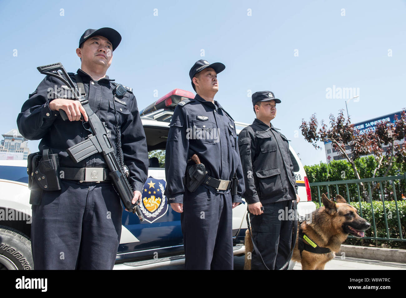 Chinese police officers armed with guns stand guard with a police dog in front of a patrol vehicle on a street in Beijing, China, 12 May 2014.   Beiji Stock Photo