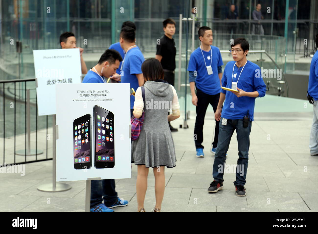 Employees stand next to an advertisement for iPhone 6 and iPhone 6 Plus smartphones outside the Apple Store in the Lujiazui Financial District in Pudo Stock Photo