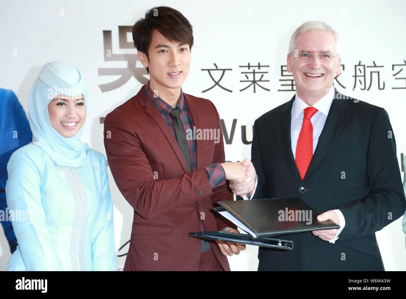 Bruneian actor Wu Chun, center, shakes hands with Royal Brunei Airlines president Dermot Mannion, right, during a signing ceremony for becoming the in Stock Photo